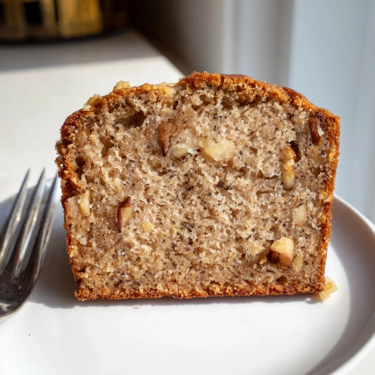 Warm Simple Banana Bread loaf, golden brown and gently sliced, ready to eat alongside coffee.