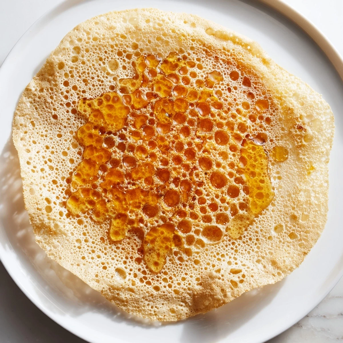 A close-up of the spongy, bubbly surface of freshly cooked Moroccan Baghrir, ready for a drizzle.