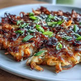 A stack of savory Korean kimchi pancakes, crispy edges with a soft, flavorful center, served with a soy-sesame dipping sauce.  