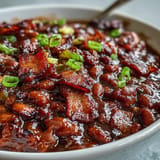 Close-up of bubbling Juneteenth BBQ baked beans with glistening bacon pieces.