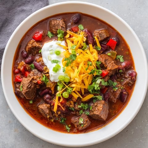A steaming bowl of Winter Warming Chili con Carne, with rich brown beef and colorful peppers.