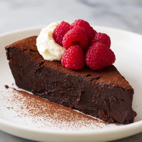 Warm, rich slice of decadent flourless chocolate cake, perfect served with fresh berries and cream.