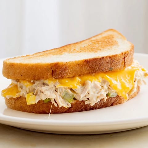 Golden-brown Classic Tuna Melt Sandwich with melted cheese oozing between toasted bread slices ready to serve.