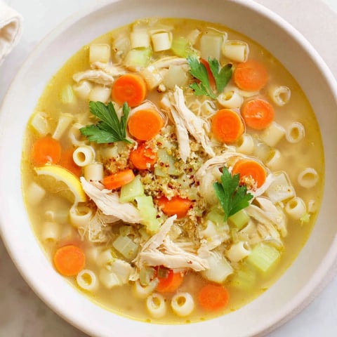 Steaming bowl of Chicken and Ditalini Flu Fighter Soup, garnished with fresh parsley and lemon wedges.