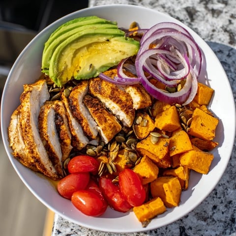Vibrant Avocado and Sweet Potato Chicken Bowl with grilled chicken, drizzled with fiery hot honey, looks delicious.