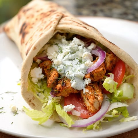 Warm Greek Chicken Souvlaki wraps overflowing with grilled chicken, tzatziki, and fresh vegetables for a delicious meal.