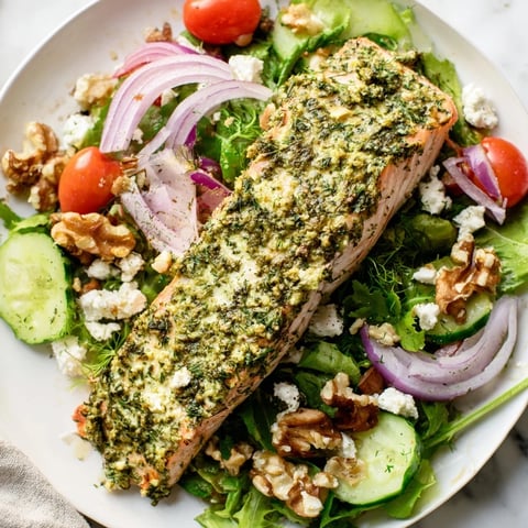 Flaky, herb-crusted salmon salad with vibrant greens, tomatoes, red onion, and a zesty vinaigrette.