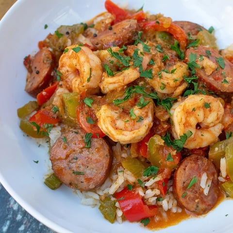 Steaming hot Jambalaya skillet, with plump shrimp, sausage, and colorful bell peppers.