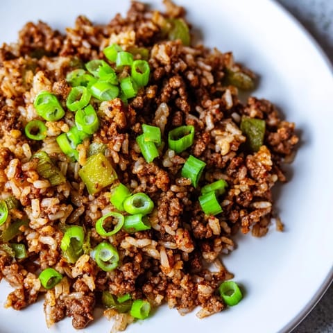 A close-up of Cajun Dirty Rice, garnished with green onions, ready for a hearty meal.