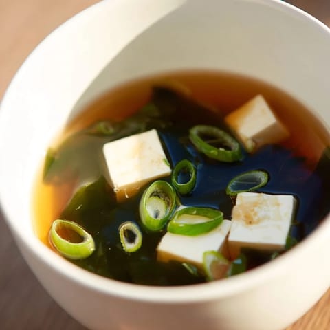 A close-up of vibrant Wakame Soup, highlighting seaweed and silken tofu in dashi broth.