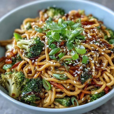 Close-up view of Asian Teriyaki Noodle Bowl showcasing glistening sauce and fresh vegetables.