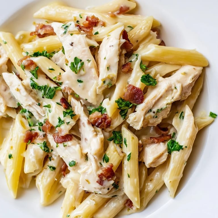 A comforting plate of Creamy Chicken Bacon Penne on a rustic wooden table, steam rising from the creamy pasta, paired with a glass of crisp white wine.