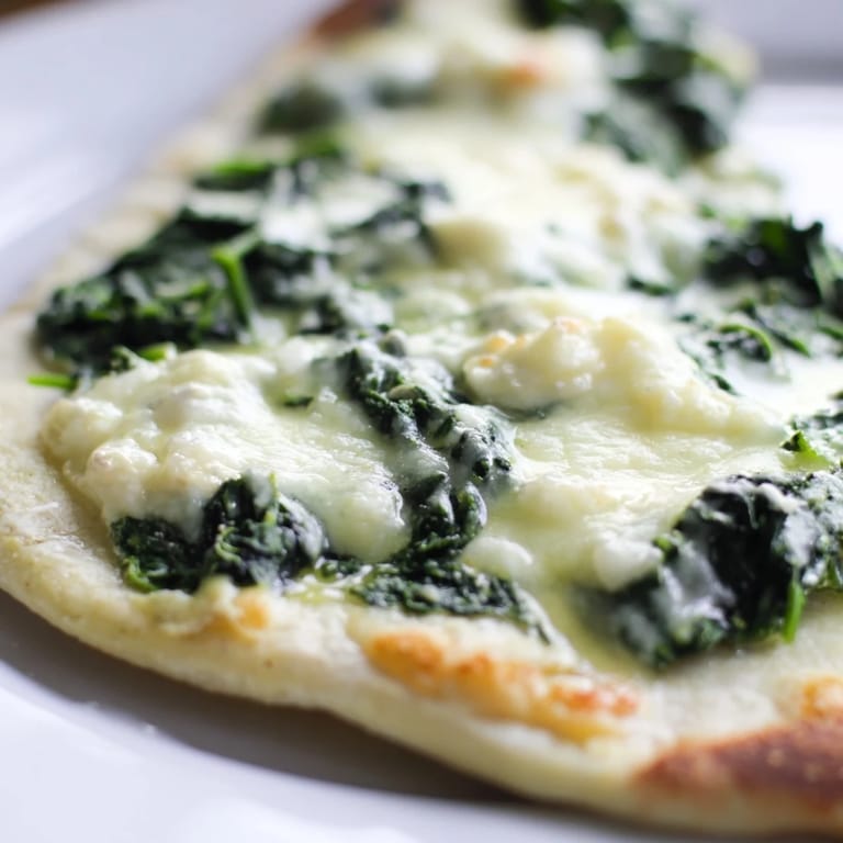 Sizzling spinach ricotta pizza fresh from the oven, with melted mozzarella and fragrant garlic butter on a rustic board.