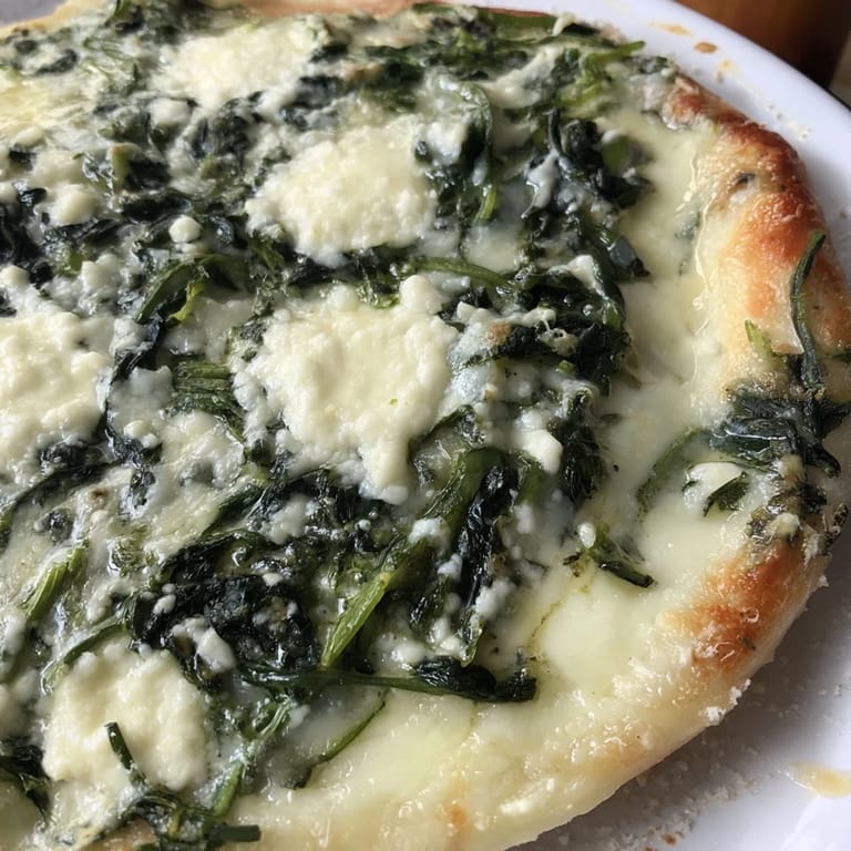 Spinach ricotta pizza slice on a white plate, revealing golden crust and creamy toppings for an easy vegetarian dinner.