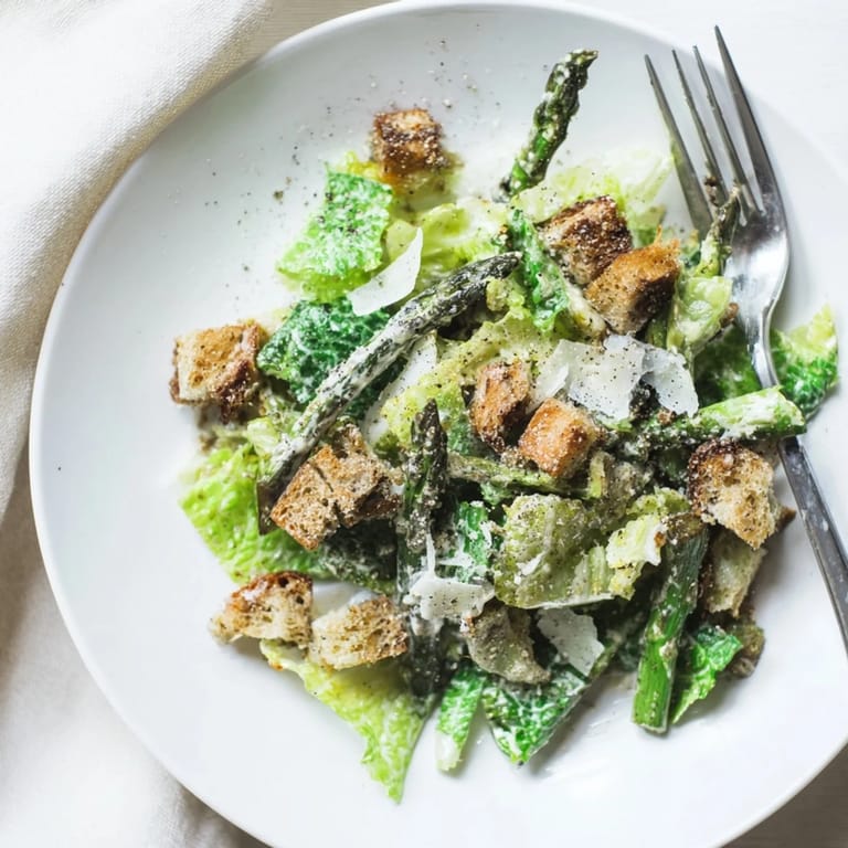 A close-up view of a healthy vegetarian Roasted Asparagus Caesar Salad with charred vegetables and golden croutons for texture.