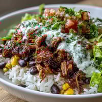 Close-up of a Carnitas Burrito Bowl with tender slow-cooked pork, fluffy rice, and black beans.