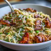 Golden one-pot lemon orzo with chicken and peas, a vibrant spring meal.
