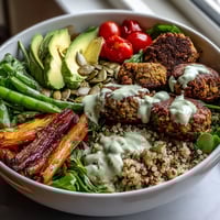 A colorful spring Buddha bowl with roasted vegetables, crispy falafel, and lemon-tahini dressing.  