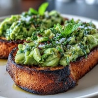 Vibrant fava bean and mint bruschetta topping grilled sourdough, a fresh spring appetizer.